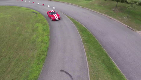 Red-dodge-viper-car-with-white-straps-on-a-race-circuit-aerial-drone-overhead